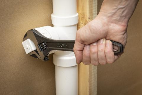 man using wrench on plumbing